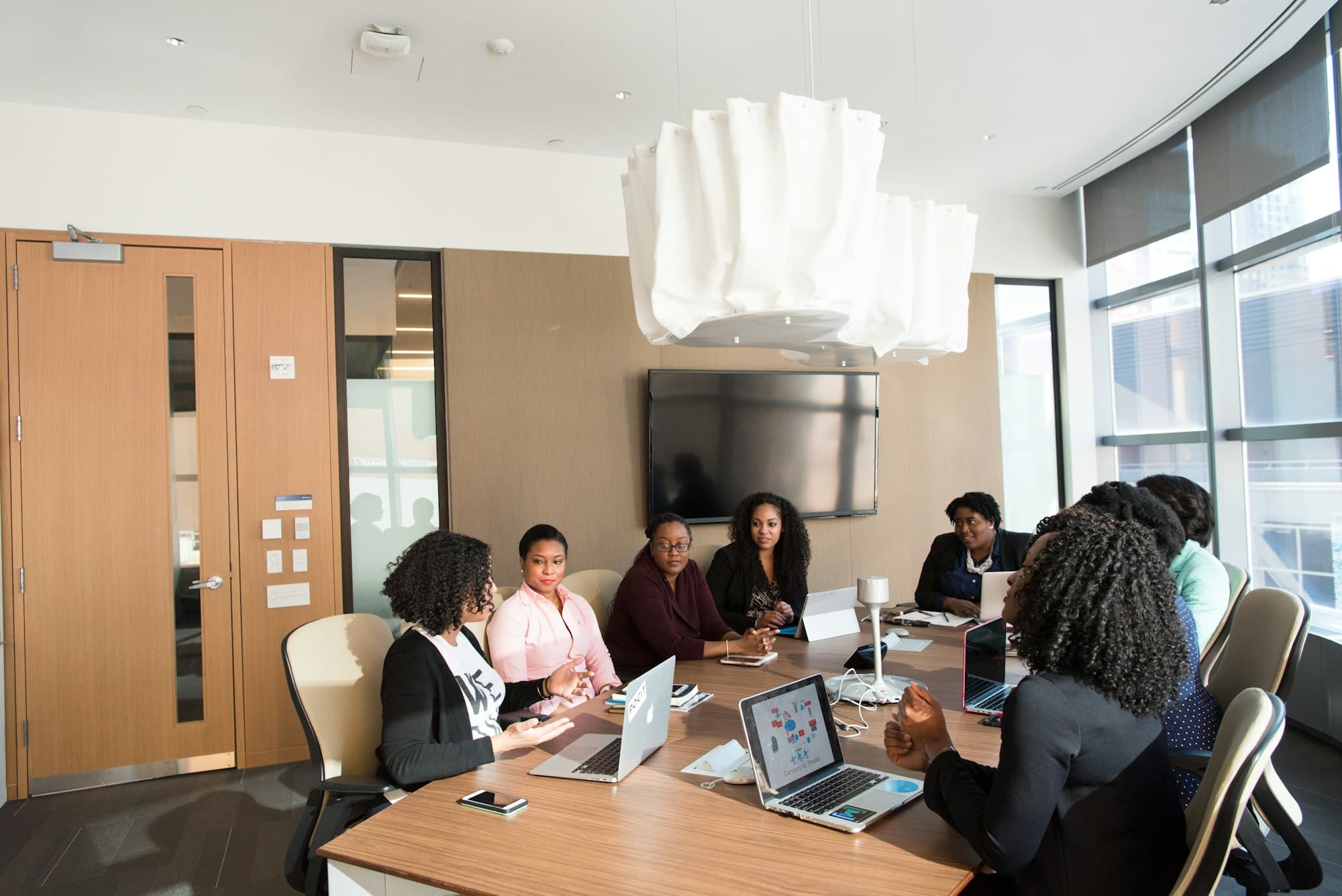 Professionals collaborating around a boardroom table with laptops